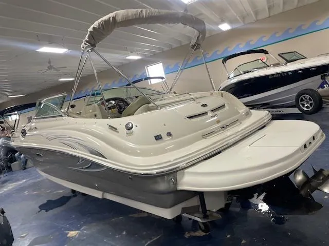 Slide: The Image of 2006 Sea Ray 240 Sundeck boat in indoor showroom with canopy and sleek design. - 2
