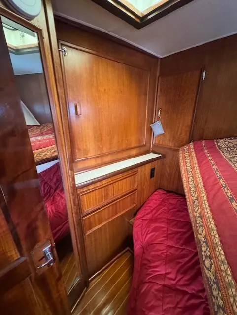 Slide: The Image of 1978 Hatteras 58 Cockpit Motor Yacht cabin with wood paneling and red bedding. - 25