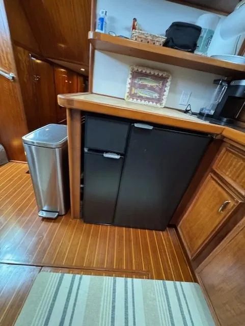 Slide: The Image of 1978 Hatteras 58 Cockpit Motor Yacht interior with wood flooring, mini fridge, and kitchen counter. - 37