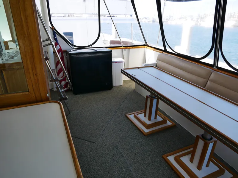 Slide: The Image of 1978 Hatteras 58 Cockpit Motor Yacht interior with seating, table, and American flag. - 42