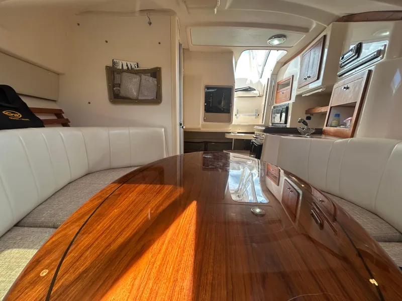 Slide: The Image of Interior of 2007 Grady-White Express 305 boat with polished wood table and white seating. - 12