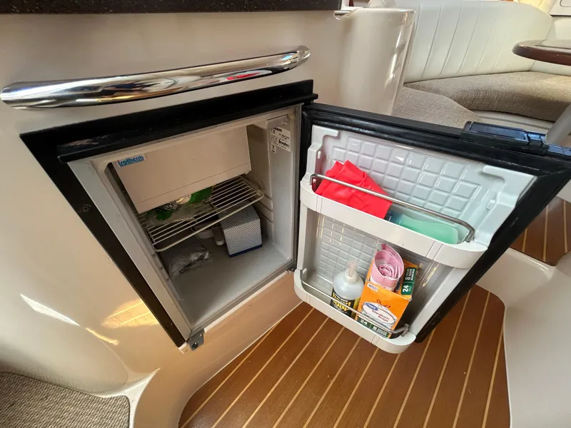 Slide: The Image of Open mini fridge on 2007 Grady-White Express 305 boat, showing interior contents and wooden flooring. - 14