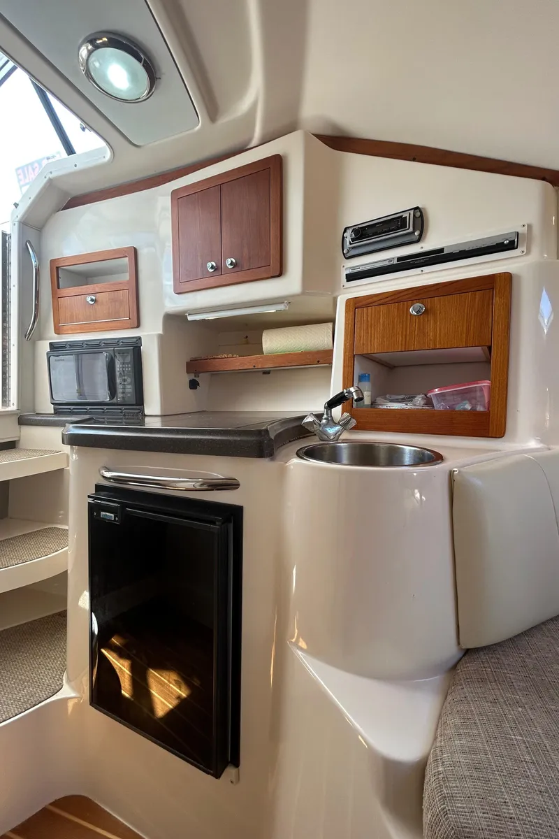 Slide: The Image of 2007 Grady-White Express 305 cabin interior with kitchenette, featuring sink, fridge, and storage cabinets. - 16