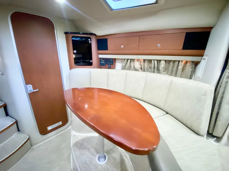 Slide: The Image of 2004 Chaparral Signature 330 cabin interior with wood table and beige seating. - 19