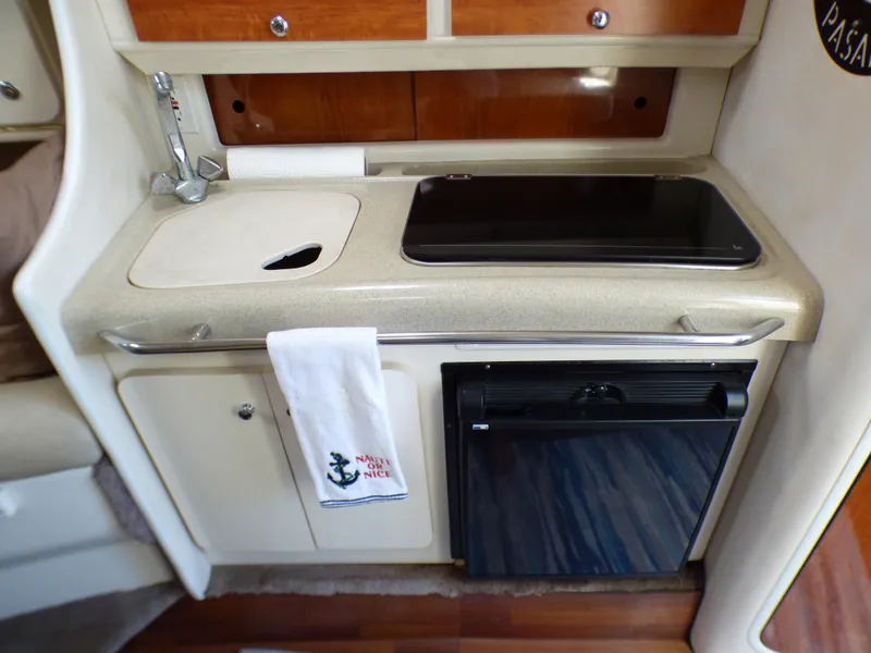 Slide: The Image of Compact kitchen area in a 2001 Monterey 302 Cruiser boat, featuring a sink and mini fridge. - 21