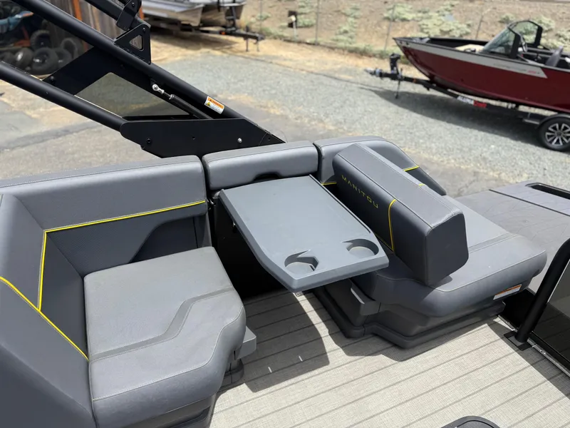 Slide: The Image of 2025 Manitou Explore boat interior with gray seating and foldable table. - 10