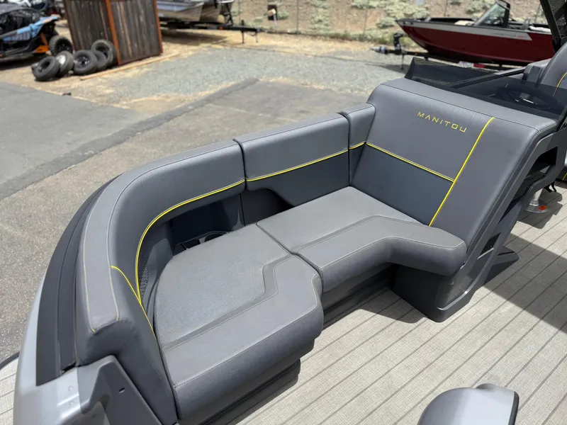 Slide: The Image of 2025 Manitou Explore boat seating with sleek gray upholstery and yellow accents. - 11