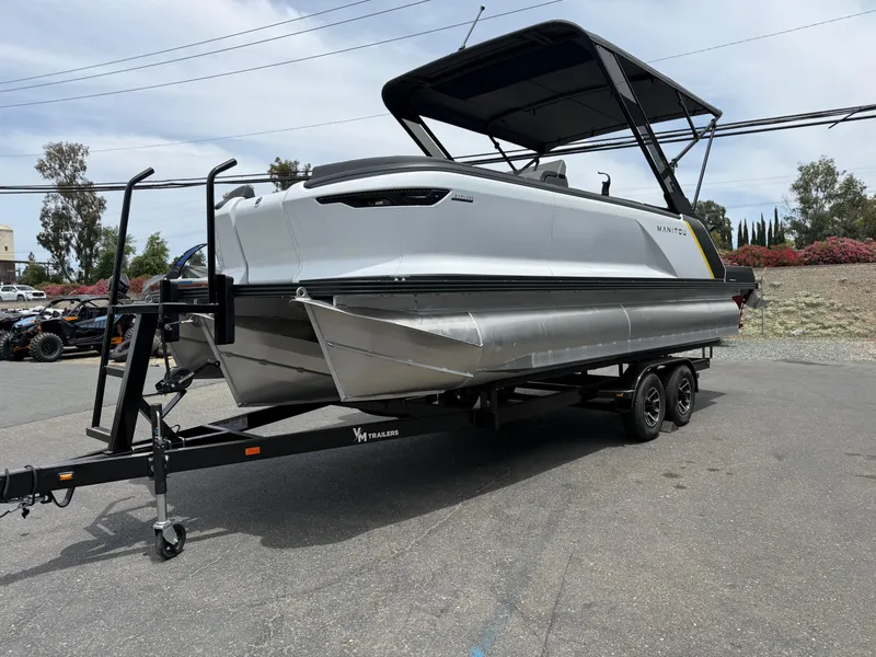 Slide: The Image of 2025 Manitou Explore pontoon boat on trailer, parked outdoors. - 3