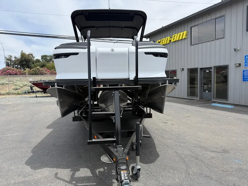 Slide: The Image of 2025 Manitou Explore boat on trailer outside dealership. - 4