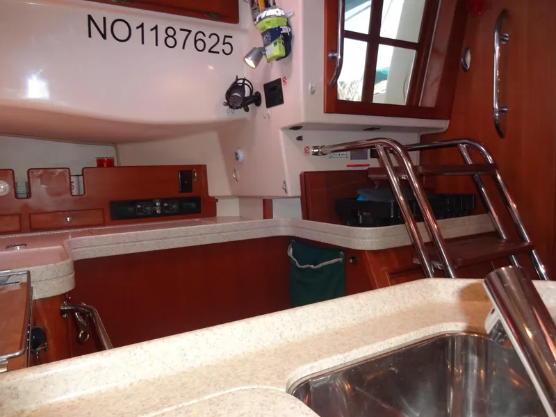 Slide: The Image of Interior of 2006 Island Packet 440 yacht, featuring a compact kitchen and wooden cabinetry. - 12