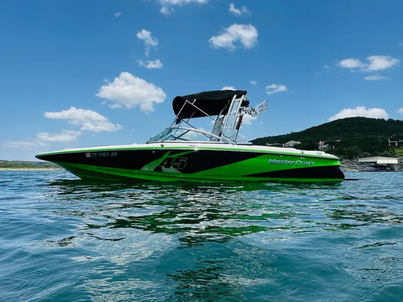 Slide: The Image of 2012 MasterCraft X-45 boat on water, vibrant green and black design, under clear blue sky. - 0