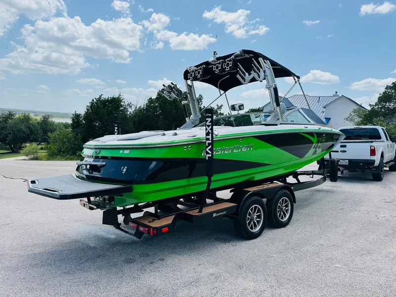 Slide: The Image of 2012 MasterCraft X-45 boat in vibrant green on a trailer, parked outdoors. - 10