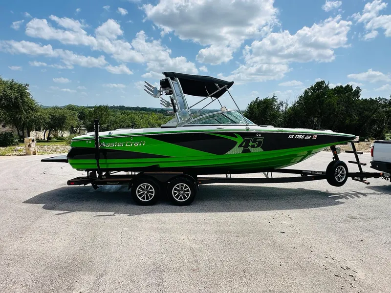 Slide: The Image of 2012 MasterCraft X-45 boat in vibrant green on a trailer, parked outdoors. - 11