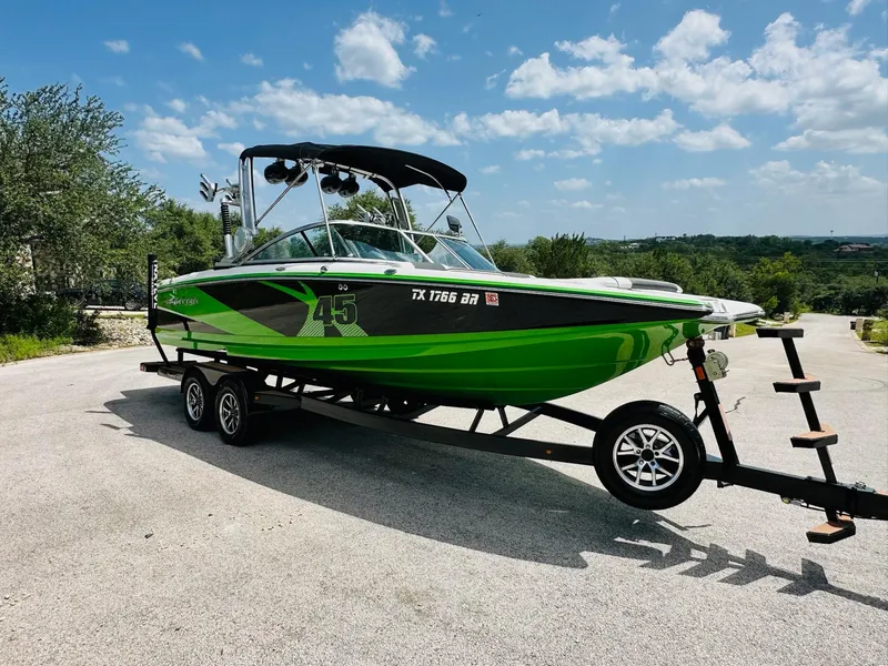 Slide: The Image of 2012 MasterCraft X-45 boat in vibrant green on a trailer under a sunny sky. - 13