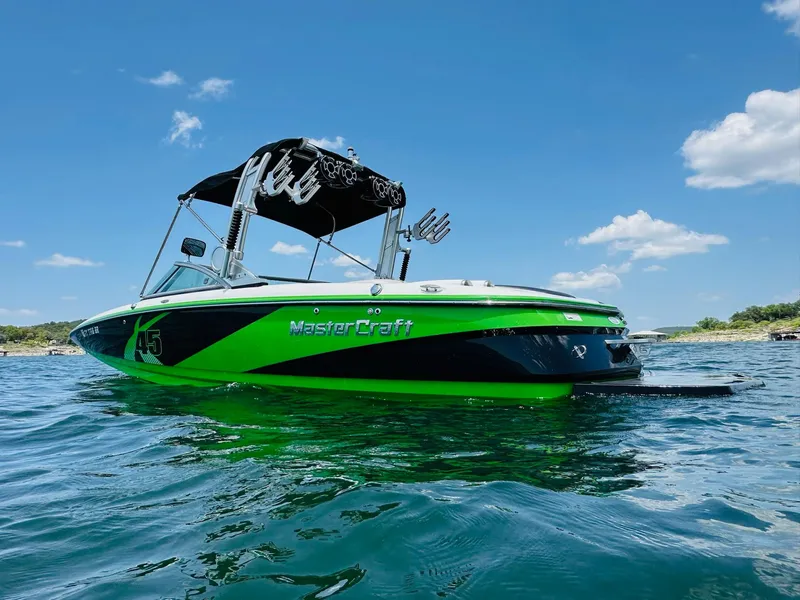 Slide: The Image of 2012 MasterCraft X-45 boat on water, vibrant green and black design, under clear blue sky. - 2