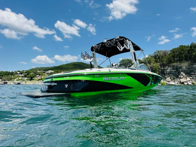 Slide: The Image of 2012 MasterCraft X-45 boat on a lake with clear skies and rocky shoreline. - 3