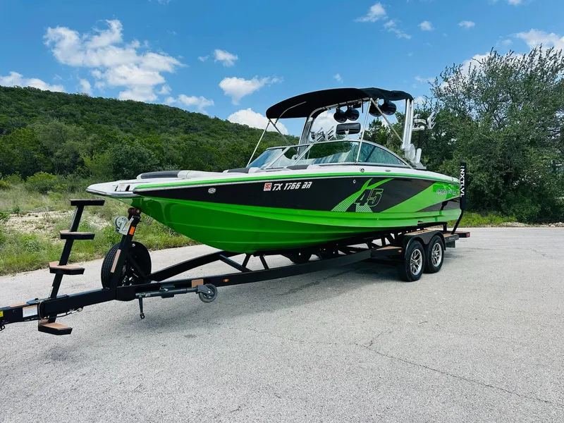 Slide: The Image of 2012 MasterCraft X-45 boat in vibrant green on a trailer, set against a scenic backdrop. - 7