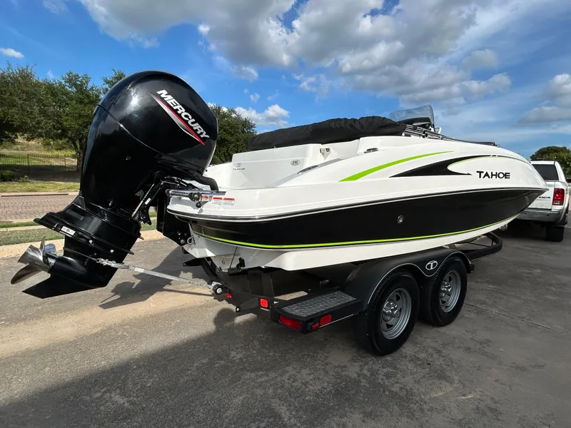 Slide: The Image of 2020 Tahoe 2150 CC boat with Mercury outboard motor on a trailer, parked outdoors. - 1