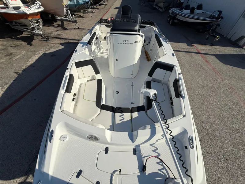 Slide: The Image of 2020 Tahoe 2150 CC boat interior with seating and steering console, parked outdoors. - 19
