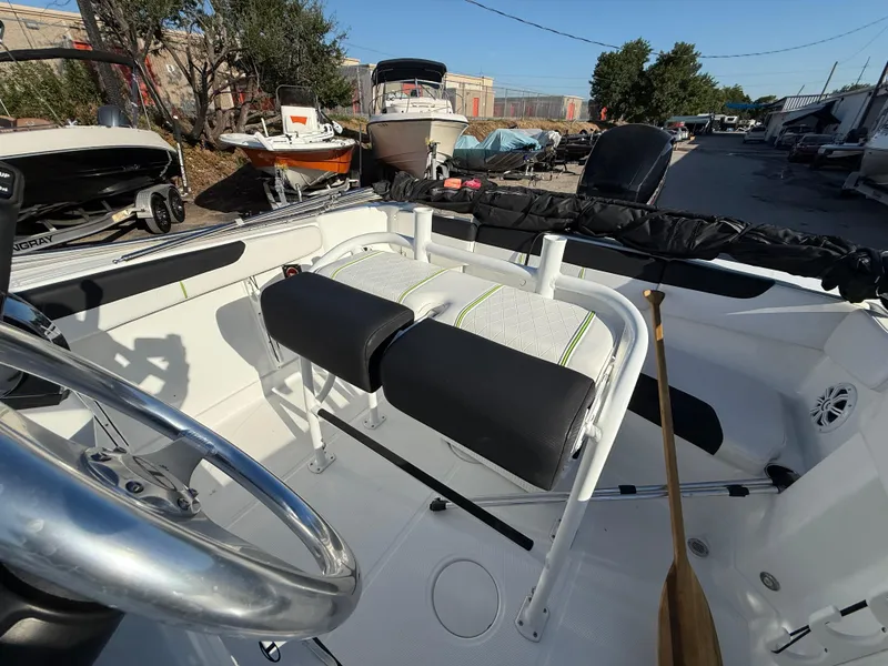 Slide: The Image of 2020 Tahoe 2150 CC boat interior with steering wheel and seating in a marina setting. - 30