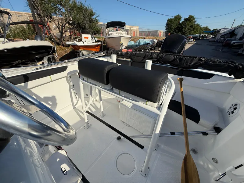 Slide: The Image of 2020 Tahoe 2150 CC boat interior with steering wheel and seating in a marina setting. - 31