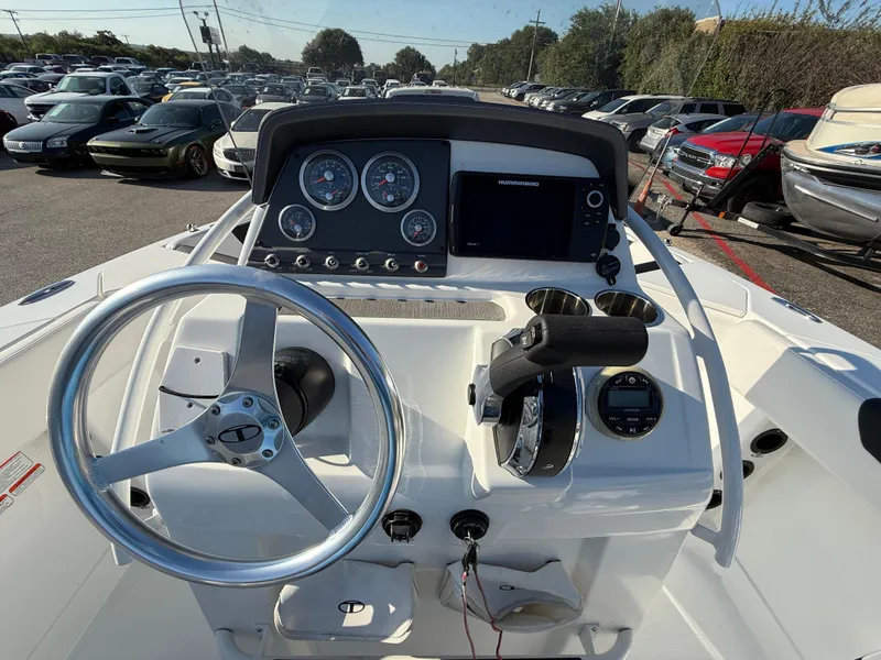 Slide: The Image of 2020 Tahoe 2150 CC boat dashboard with steering wheel and control panel in a parking lot. - 32