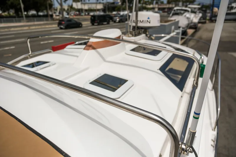 Slide: The Image of 2018 Ranger Tugs R-23 boat deck with railings and hatches, docked near a road. - 16