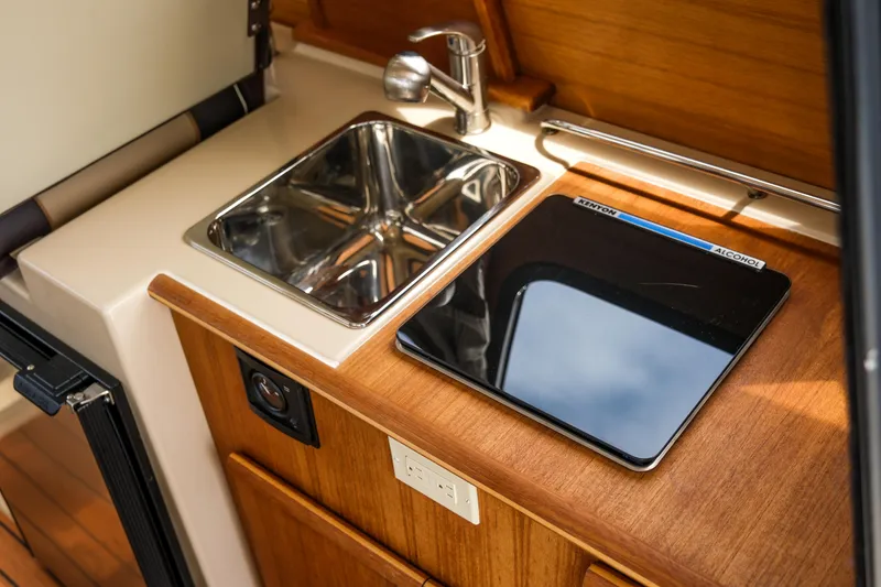Slide: The Image of Compact kitchen area in a 2018 Ranger Tugs R-23 boat, featuring a sink and stove. - 22