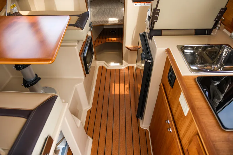 Slide: The Image of 2018 Ranger Tugs R-23 interior with wood flooring, compact kitchen, and seating area. - 23