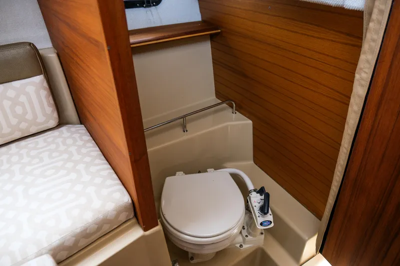 Slide: The Image of 2018 Ranger Tugs R-23 boat interior with compact marine toilet and wooden paneling. - 26