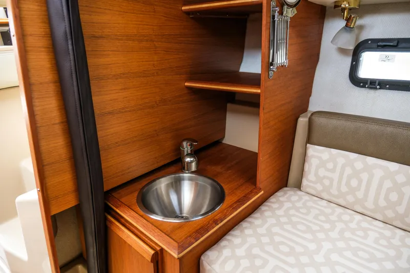 Slide: The Image of 2018 Ranger Tugs R-23 interior with wooden cabinetry, stainless steel sink, and patterned seating. - 27