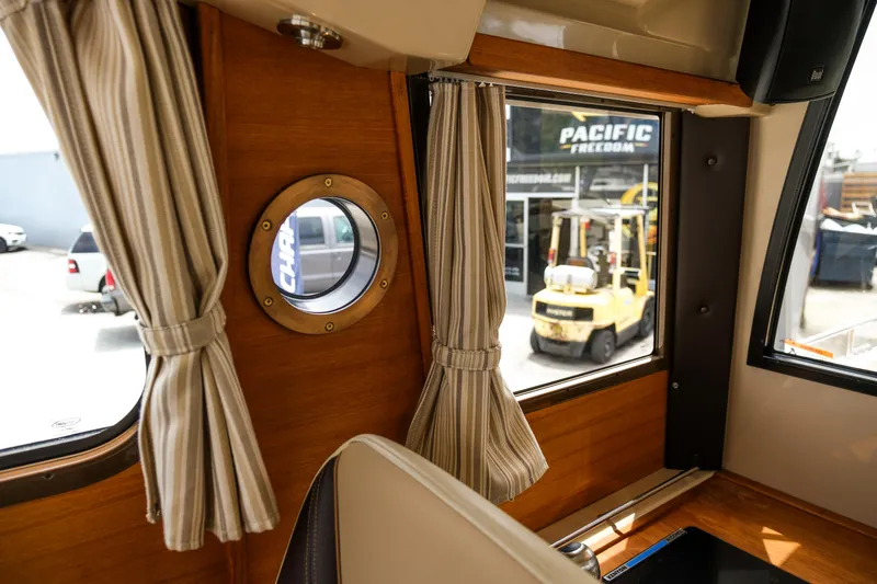Slide: The Image of Interior view of 2018 Ranger Tugs R-23 boat with striped curtains and porthole window. - 32