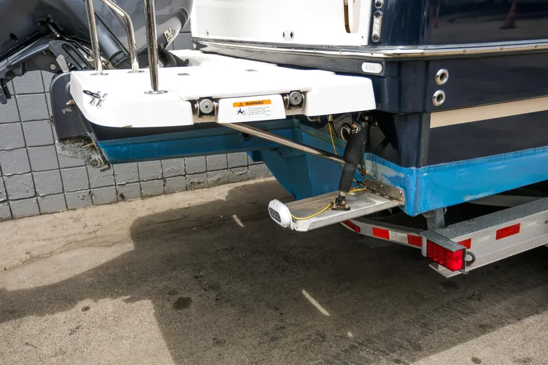 Slide: The Image of 2018 Ranger Tugs R-23 boat stern with motor and trailer, parked on concrete. - 7