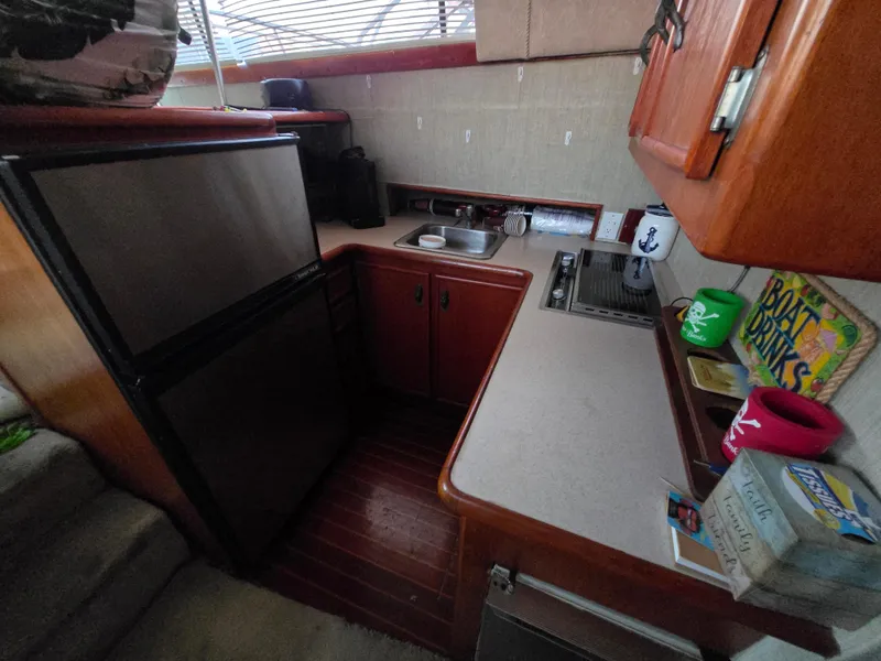 Slide: The Image of Compact kitchen area in a 1988 Ocean 35 Super Sport boat with wooden cabinets and appliances. - 13