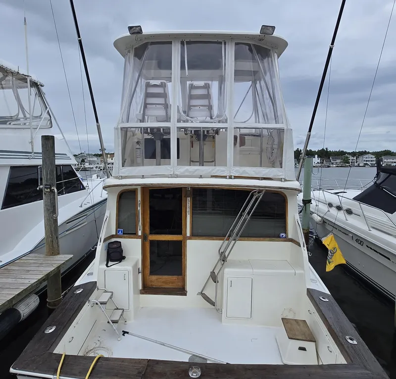 Slide: The Image of 1988 Ocean 35 Super Sport yacht docked at marina, featuring spacious deck and enclosed upper helm. - 38
