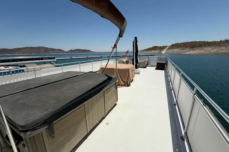 Slide: The Image of 2001 Sumerset 18x104 houseboat deck with hot tub, lake view, and clear sky. - 75