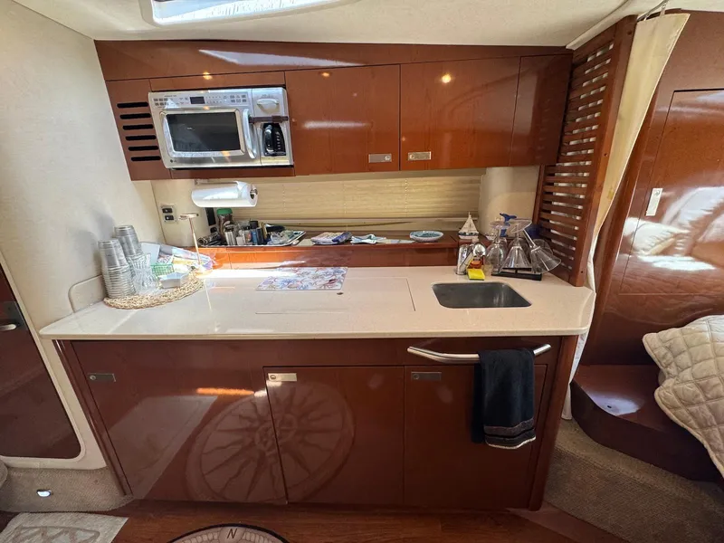 Slide: The Image of 2008 Sea Ray 350 Sundancer yacht interior kitchen with microwave, sink, and wooden cabinetry. - 27