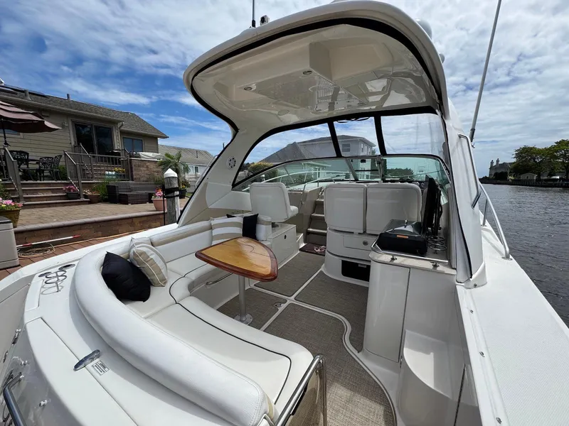 Slide: The Image of 2008 Sea Ray 350 Sundancer boat interior with seating and table, docked by waterfront homes. - 3