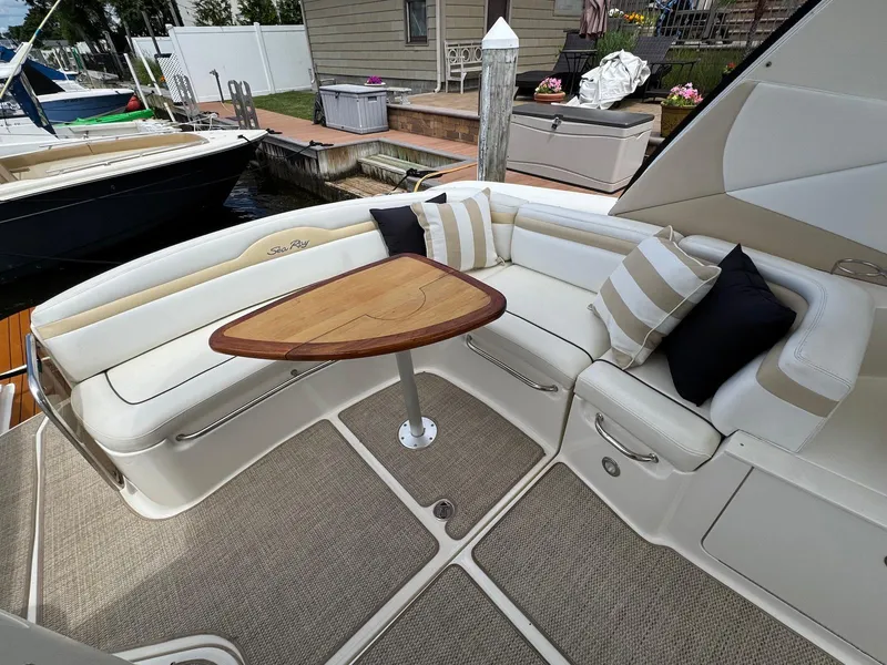 Slide: The Image of 2008 Sea Ray 350 Sundancer boat interior with cushioned seating and wooden table. - 6