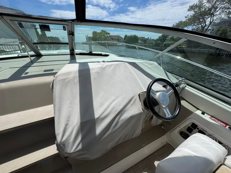 Slide: The Image of 2008 Sea Ray 350 Sundancer cockpit with covered dashboard and steering wheel, overlooking waterway. - 8