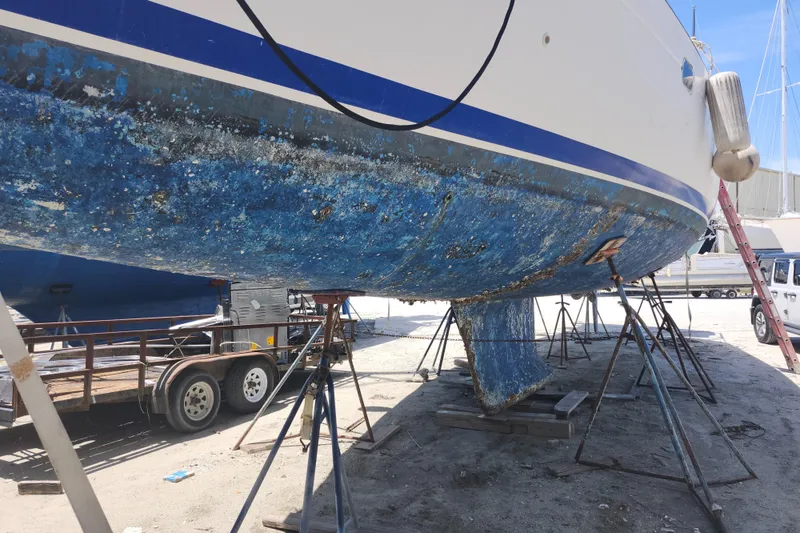 Slide: The Image of Beneteau 50 sailboat from 2003 on stands, showing worn blue hull paint. - 12