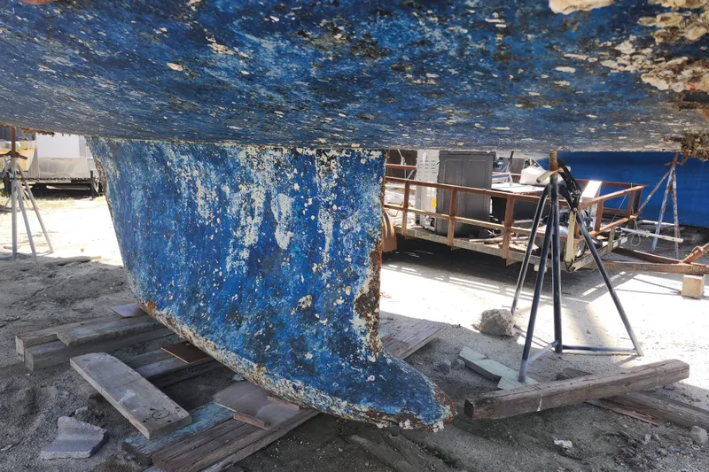 Slide: The Image of Aging hull of 2003 Beneteau 50 sailboat on dry dock, showing wear and marine growth. - 14
