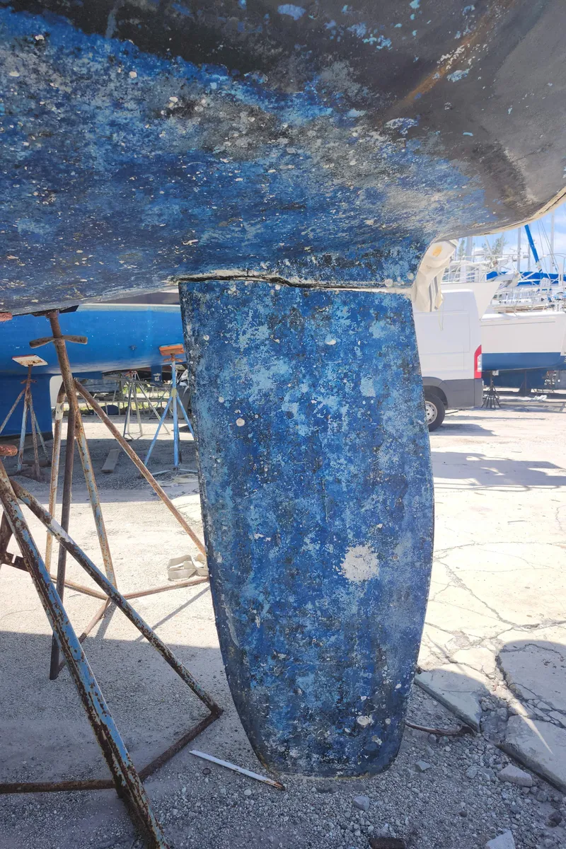 Slide: The Image of Beneteau 50 sailboat keel, 2003 model, with blue paint and visible wear, on dry dock. - 16