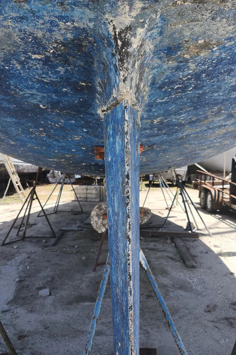 Slide: The Image of Bottom view of a 2003 Beneteau 50 sailboat hull on stands, showing weathered blue paint. - 17