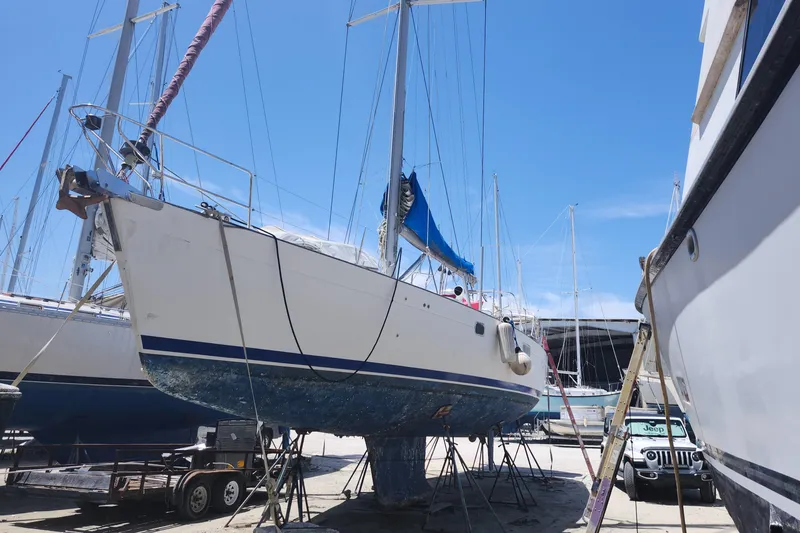 Slide: The Image of Beneteau 50 sailboat from 2003 on dry dock, surrounded by other boats under clear blue sky. - 2