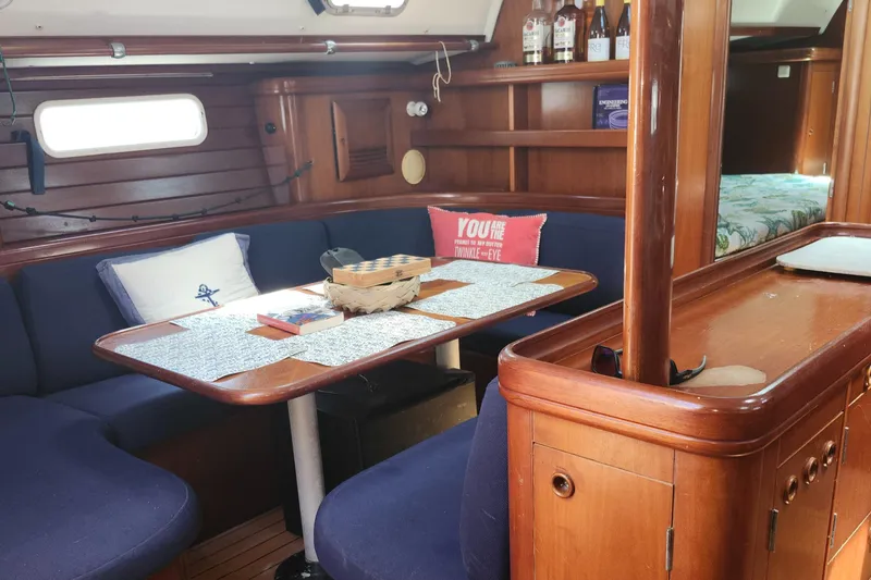 Slide: The Image of Cozy interior of 2003 Beneteau 50 sailboat with wooden furnishings and blue seating. - 26