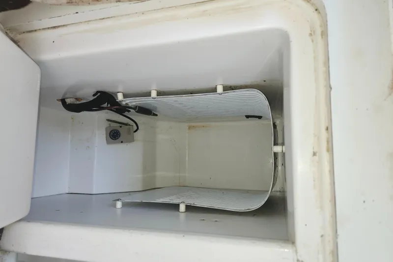 Slide: The Image of Empty storage compartment inside a 2003 Beneteau 50 yacht, featuring a cooling unit. - 39
