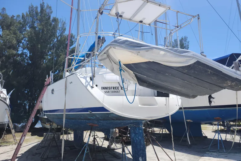 Slide: The Image of 2003 Beneteau 50 sailboat on dry dock, with trees and clear sky background. - 4