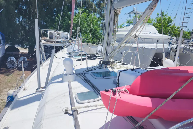 Slide: The Image of Beneteau 50 sailboat deck with pink kayak, 2003 model, docked under clear blue sky. - 8