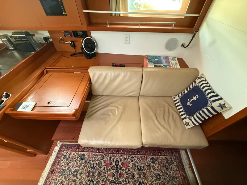 Slide: The Image of Interior of 2016 Beneteau Oceanis 45 with beige seating, nautical pillow, and wooden accents. - 2